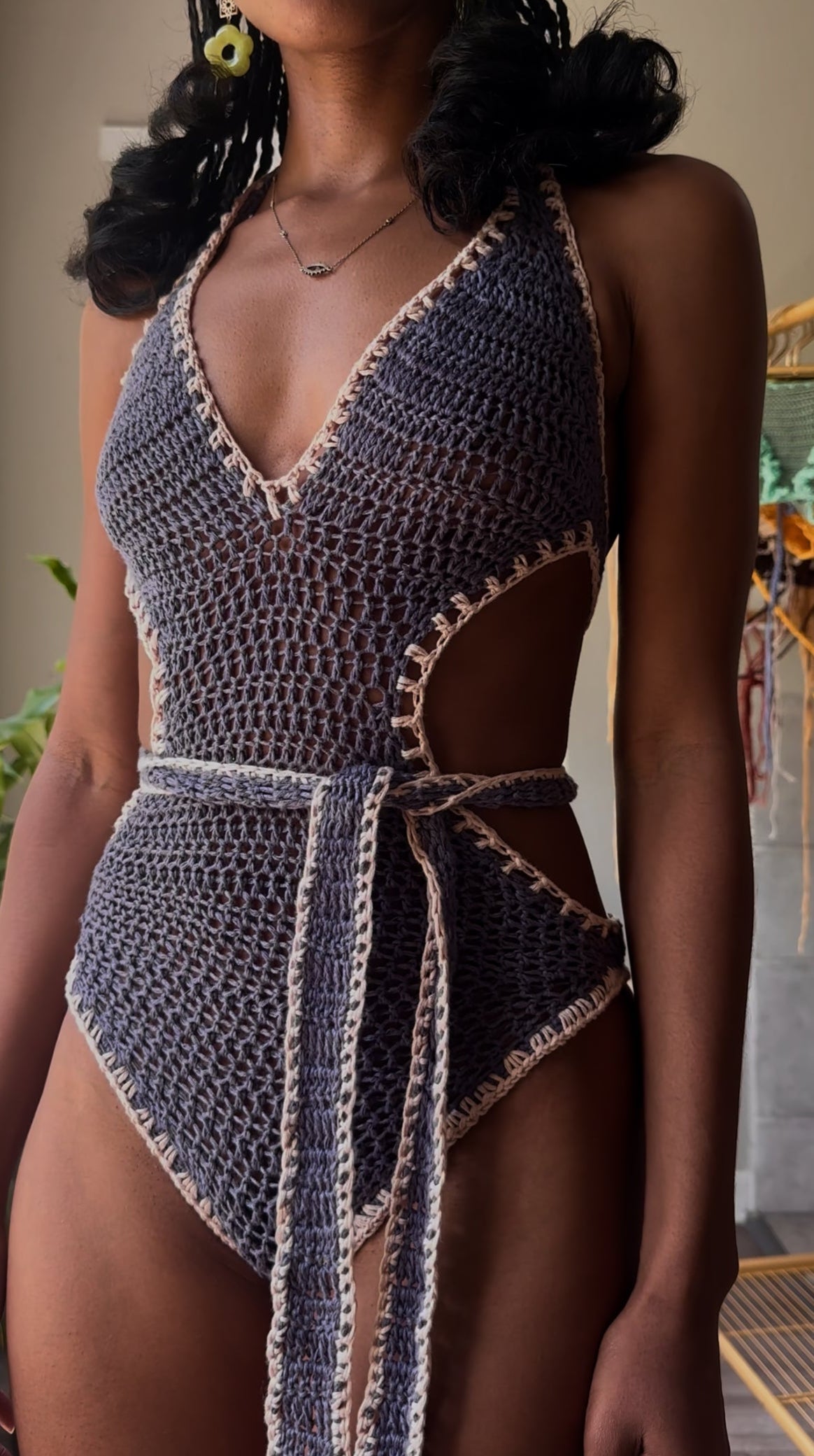 Person wearing a crochet swimsuit with a neutral background
